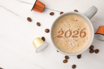 New 2026 Year card with cup of coffee and roasted beans on white wooden table, top view