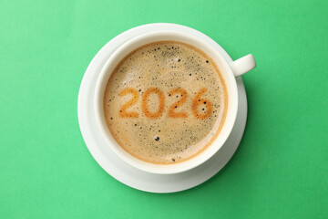 Hello New 2026 Year. Cup of coffee with numbers on green background, top view