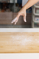 Close-up hand of asian young woman sprinkling flour over wooden cutting board for homemade bread cooking on table in kitchen, preparation ingredients process making food desserts bakery baking concept