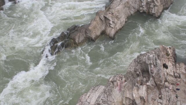 dramatic aerial perspective of the rushing narmada river as it surges through rocky formations at 'dhuandhar' waterfall, captured from  ropeway car at 'bhedaghat', jabalpur