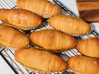 Top view of freshly baked salted butter roll bread on baking wire rack tray, Golden brown texture, homemade bakery concept, warm delicious pastry background, ready to serve buns in small local kitchen