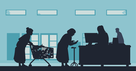 A mature elderly woman waits in line at the grocery checkout with a trolley and uses her phone to pay for her groceries. A young woman serves her at the computer.