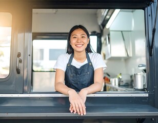 Happy young Asian female entrepreneur posing in the service window of her modern food truck.