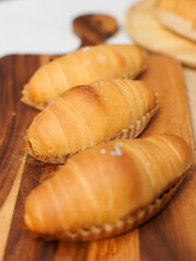 Top view of freshly baked salted butter roll bread on baking wooden cutting board, Golden brown texture, homemade bakery concept, warm delicious pastry background, ready to serve buns in small kitchen