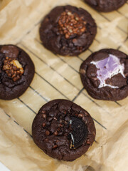 Close up freshly baked homemade dark chocolate soft cookies mixed toppings biscuits wafer marshmallow chocolate chips on baking tray parchment paper sheet, Dessert snack bakery yummy delicious tasty.