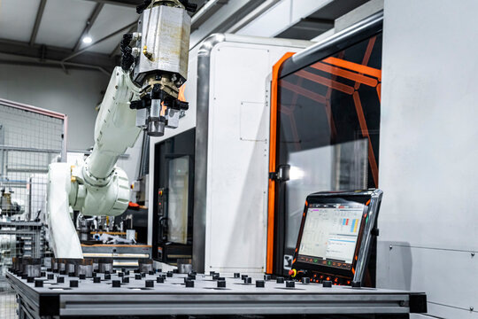 White robotic arm with cnc automated machinery in metal factory