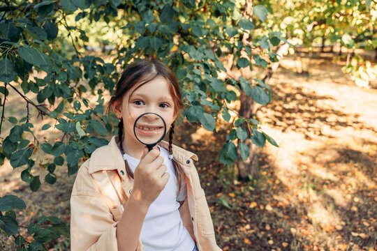 Girl smiling with magnifier exploring nature outdoors