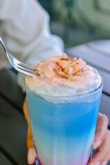 Taking a spoonful of fluffy pink whipped cream from a refreshing Cotton Candy Ice frappe (butterfly pea tea, raspberry, milk)