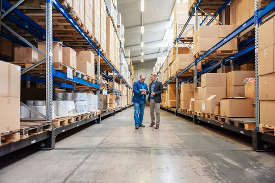 Business meeting of employees with tablet in warehouse aisle