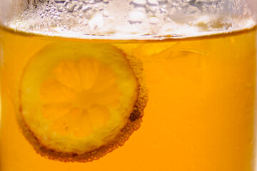 Extreme close-up macro of iced lemon tea showing the texture of a submerged dried lemon slice and...