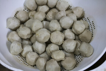 Close up view of savory cooked beef meatballs in white nder. Hearty homemade food preparation with pile of fresh ingredients ready for an Asian cuisine dish