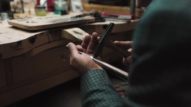 A skilled jeweler hammers a ring to shape and refine it.