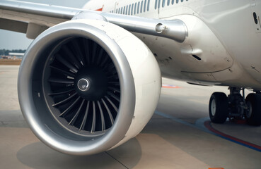 Close up photo shows an aircraft jet engine. The plane turbofan motor and wing part are visible. Aviation and aerospace industry. Transportation and flight.