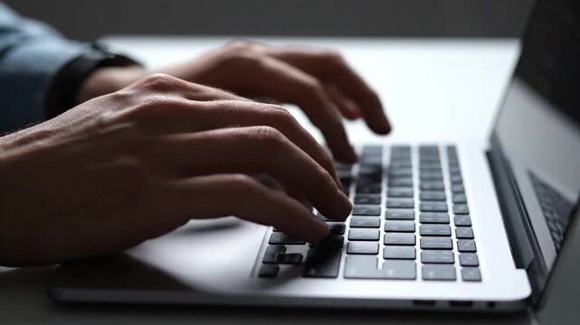 A close-up shot of hands typing on a laptop keyboard. Focus is on hands and keyboard keys