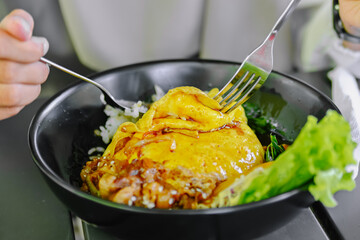 Detailed close-up of a person scooping rice and cutting the omelet (Chiffon Egg Bulgogi) with a fork, emphasizing the texture of the dish