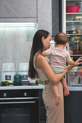  Busy Mom Holds Baby While Preparing Meal in Kitchen Tired mother struggles to cook with the baby in her arms 