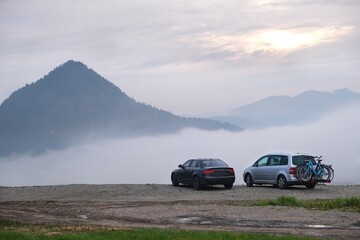 Fototapeta premium Two cars are standing on mountain viewpoint in misty scenery in Pieniny Mountains, Poland