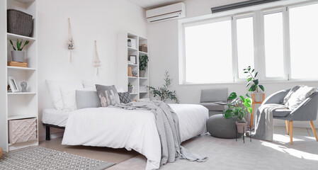 Interior of modern bedroom with shelving units and houseplants