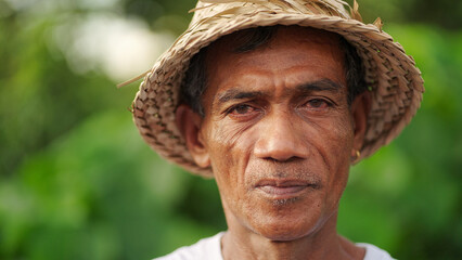 asian man farmer face in rural asia wearing a traditional hat, portrait looking to camera, headshot...