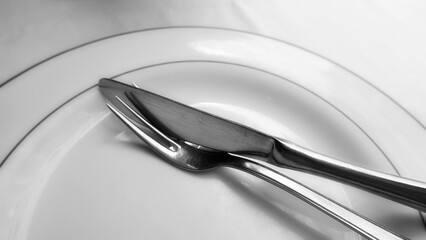 Knife And Fork On White Plate Close Up Monochrome Minimalist Image. Elegant Table Setting With...