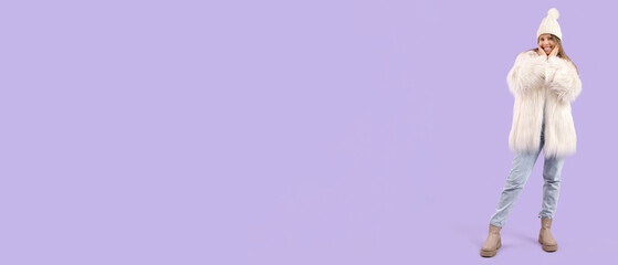 Happy young woman in winter clothes on lilac background