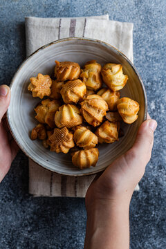 Homemade caramel profiteroles in ceramic bowl held by hands