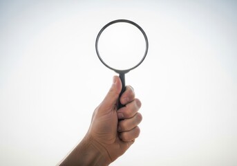 Hand holding a magnifying glass searching for details and information with bright light background
