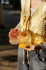 A girl holds an autumn cocktail decorated with a flower in her hands. in the sun on a summer terrace. Close-up photo