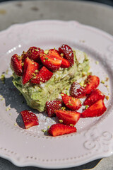 A piece of Napoleon cake with pistachio, decorated with lots of strawberries. Sweet dessert