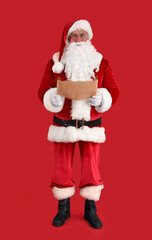 Santa Claus with wish list on red background