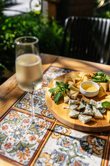 Cheese plate with various cheeses as an appetizer for wine. Camembert, Gouda, Cheddar, Dorblu and Parmesan cheese with a glass of white wine