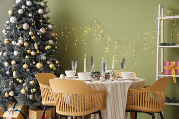Festive table setting with Christmas decorations, reindeers and burning candles in dining room