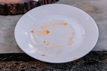 Minimalist close-up of a white ceramic plate showing orange sauce and oil remnants after a delicious meal has been finished