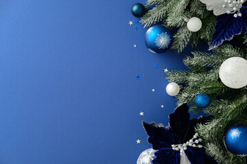 Christmas border with snowy pine, blue baubles, silver stars and poinsettia on blue background....