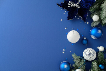 Winter holiday composition with velvet poinsettia, frosted pine, and blue ornaments on the right...