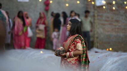 Newly married Indian woman performing Chhath Puja near water, offering coconut and praying to rising sun, symbolizing faith and divine belief.