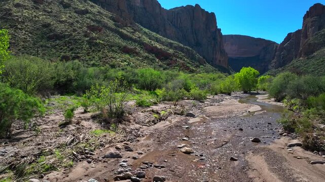 Aerial view of the rugged Apache Trail, a landscape of towering mountains, sparse vegetation, and a stream, Apache Junction, Arizona, United States.
