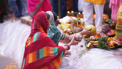 Women offering fruits and coconuts while standing in holy water during Chhath Puja sunrise ritual, showing devotion, peace, and spiritual faith.