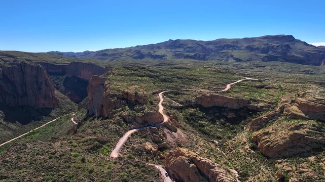 Aerial view of the winding Apache Trail road cutting through the rugged terrain, with views of the mountains, Apache Junction, Arizona, United States.