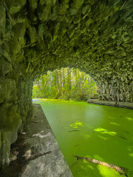 Fairy Bridge stone arch above vivid green waterway in Lough Key Forest Park, County Roscommon, Ireland, showing the bright green surface framed by woodland and moss-covered stone walls.