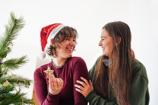 Girls decorating Christmas tree with ornaments at home