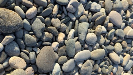 Natural assortment of smooth rounded pebbles and stones in various colors and textures, shaped by water erosion and weathering over time
