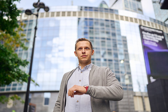 Man outdoors in urban setting checking smartwatch