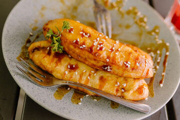 Sweet caramelized fried banana (Pisang Goreng) dessert, topped with glossy caramel sauce and served beautifully on a rustic wooden table