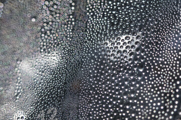Mesmerizing abstract background of water drop condensation on dark surface. macro texture view of...