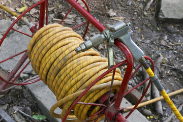 Yellow industrial air hose wrapped on red metal reel with pneumatic nozzle. Heavy duty construction...
