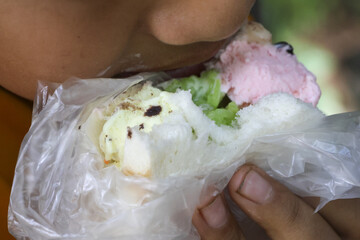 Person eating sweet colorful ice cream sandwich, popular street food snack and dessert. close up of...