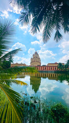 Majestic view of Dakshineswar Temple with palm reflections, bright sky, and tranquil river surroundings.