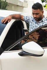 Man leaning on car using smartphone outdoors