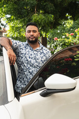 Confident man standing by car outdoors during day